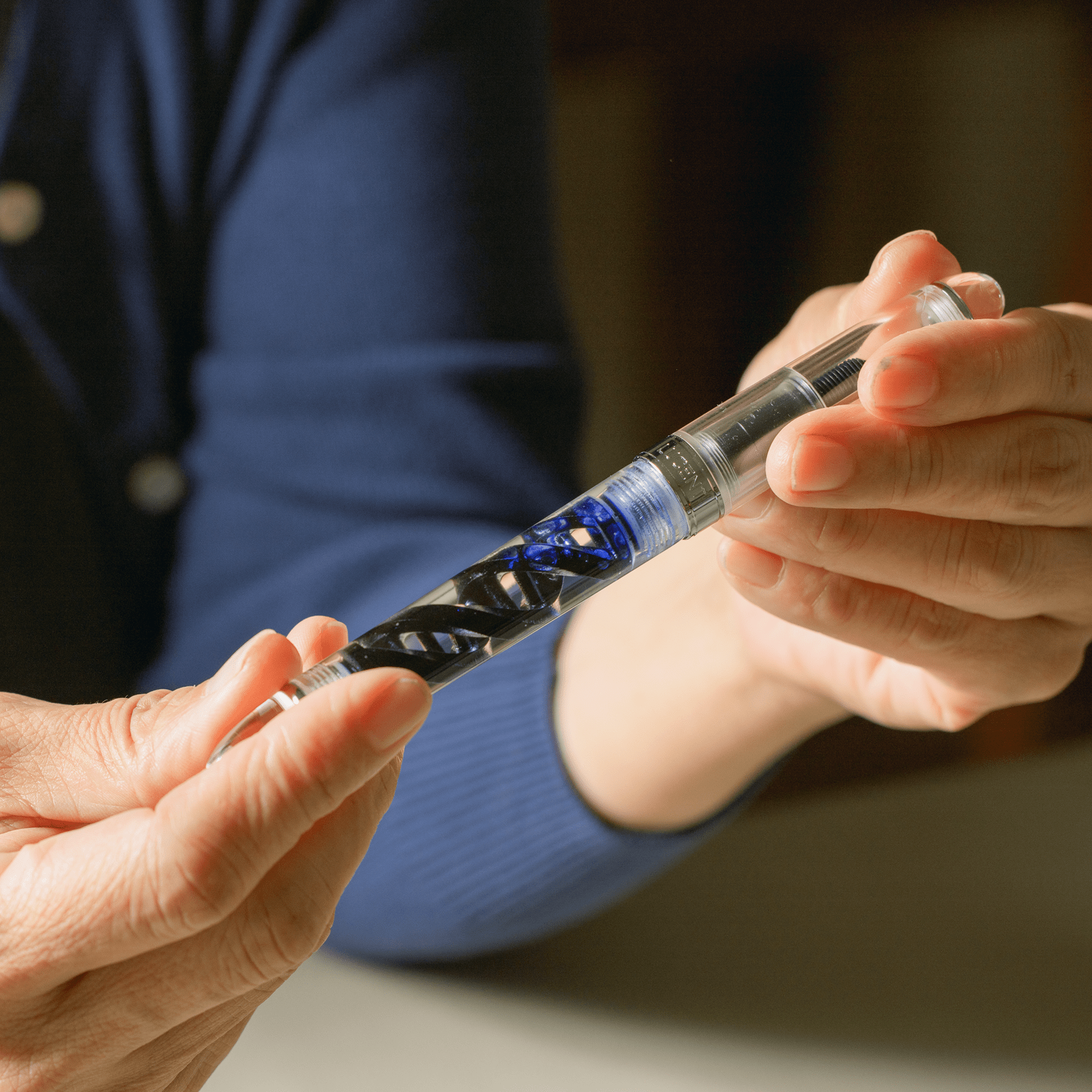 Inked DNA Lucent fountain pen held in both hands, by Hex Pens.