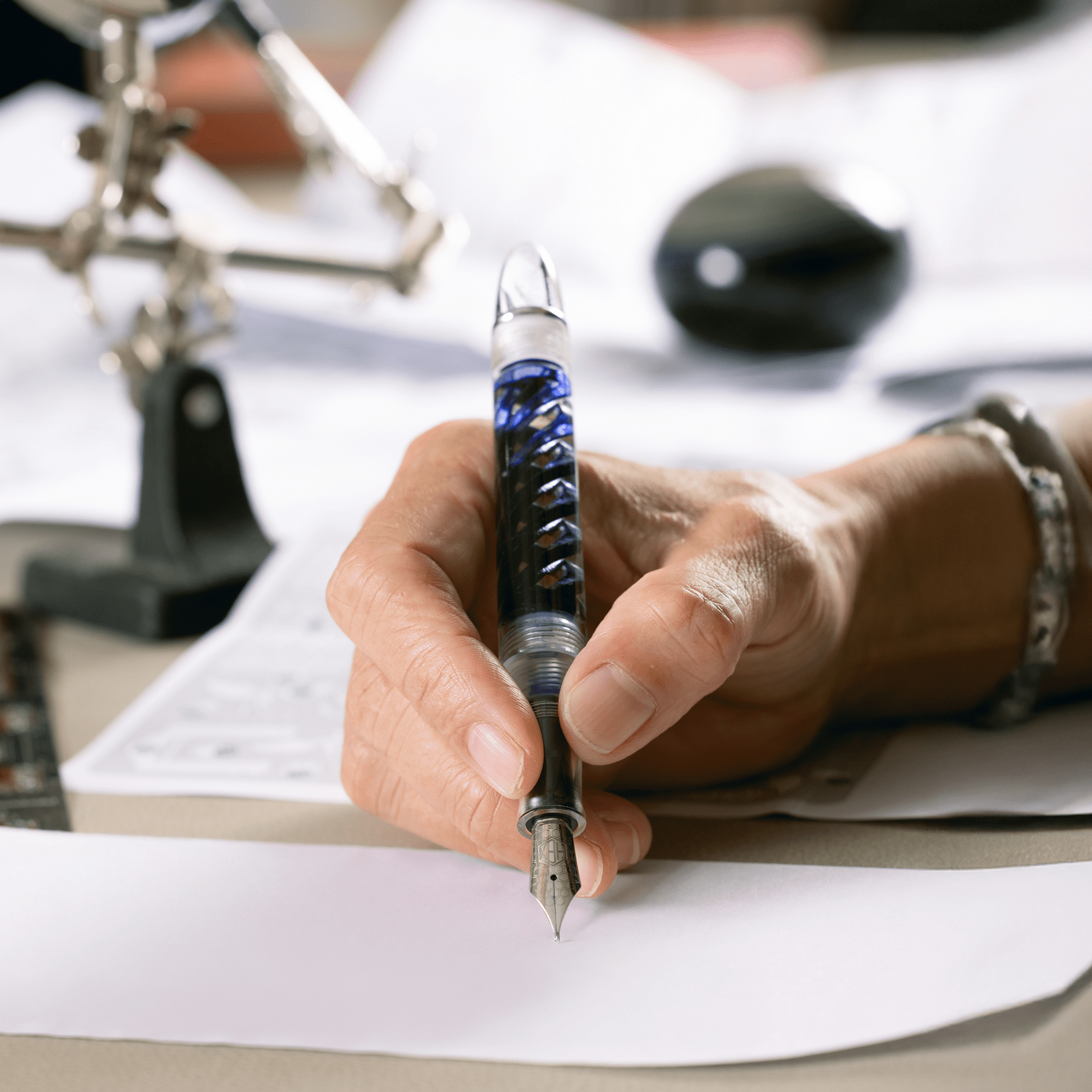 Inked Triple Twist Lucent fountain pen poised to write on paper, by Hex Pens.